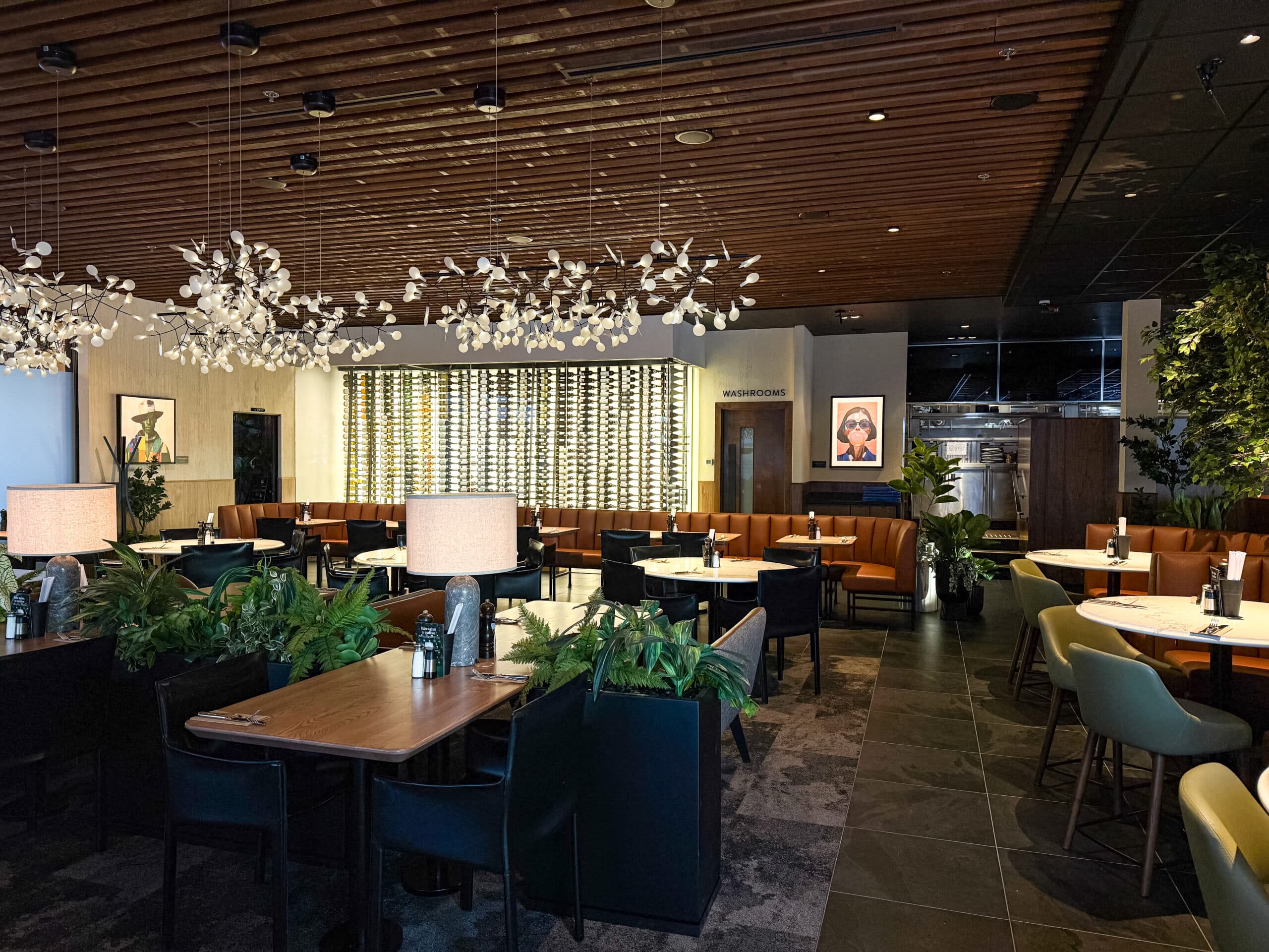 Elegant restaurant lounge illuminated by a flower-petal chandelier with a glowing backlit wine wall.